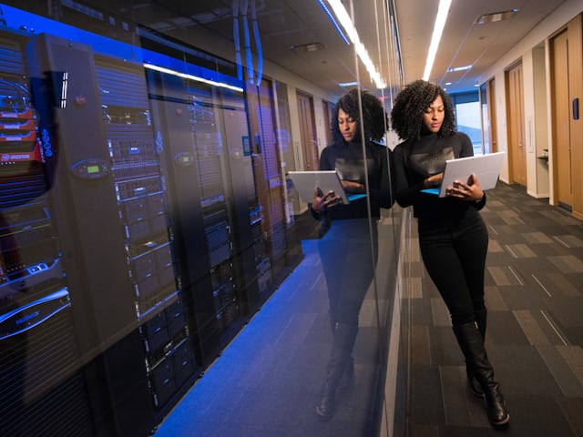 Data centre aisle with an engineer working on a laptop